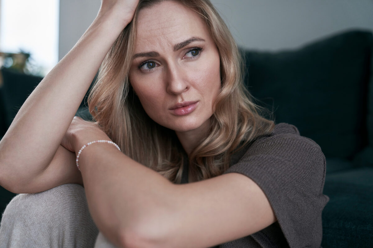 Close up of depressed woman sitting at home alone and looking away