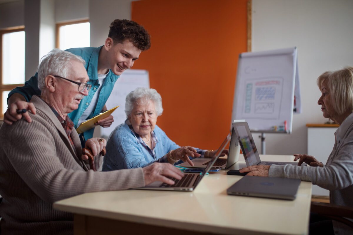 10 Reasons Older People Crave Stability While Younger People Chase Peace 1 Senior group in retirement home with young instructor learning together in computer class