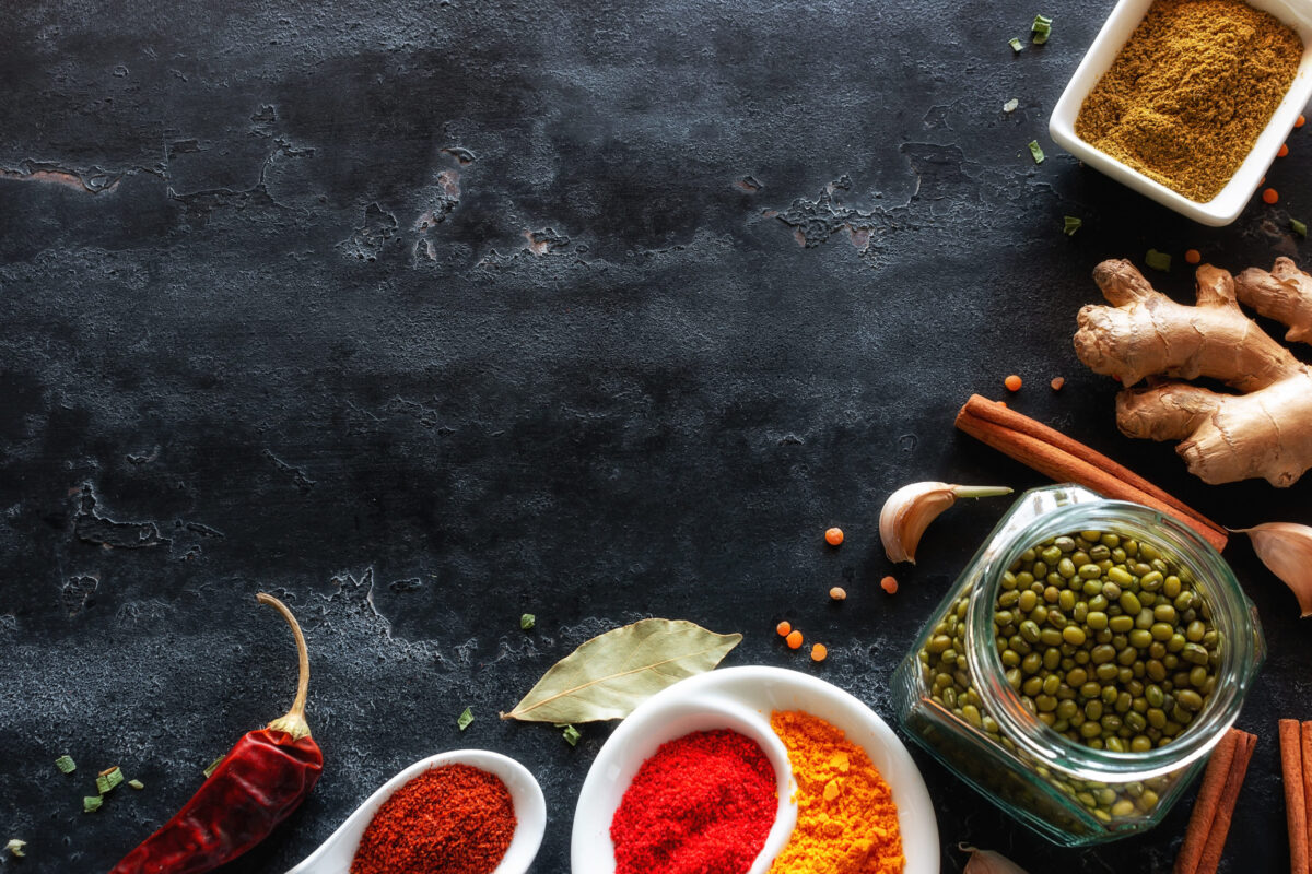 spices herbs and condiments on black kitchen table with place for text
