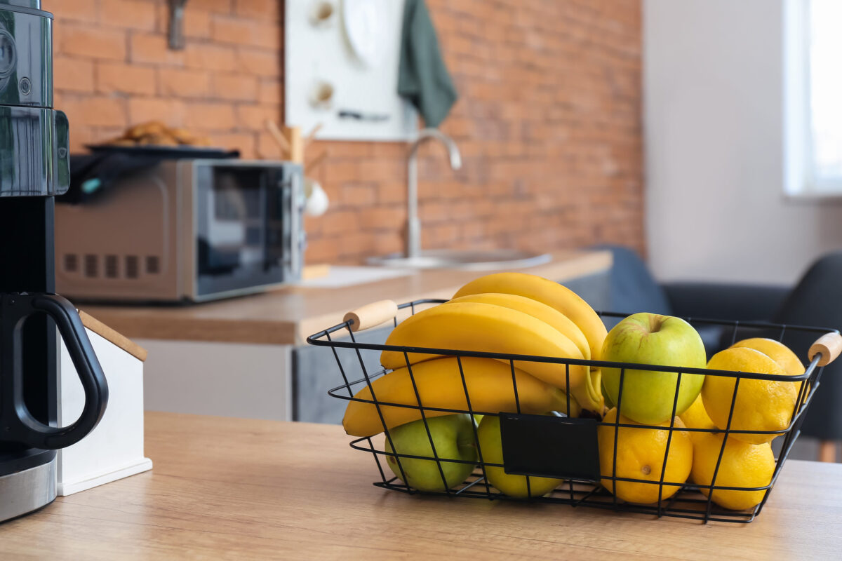 Basket with healthy fruits on table top in modern kitchen