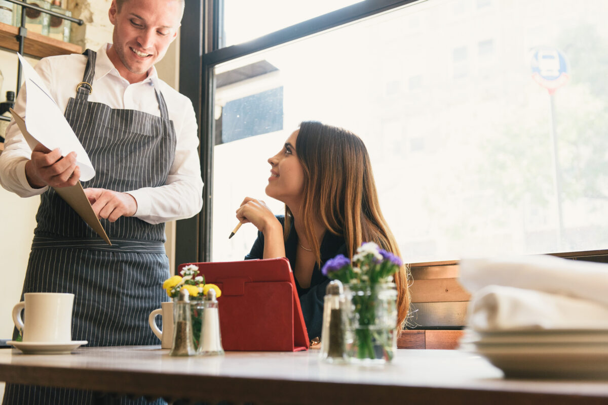 10 Restaurant Mistakes That Could Be Ruining Your Dining Experience 1 Young woman and waiter discussing menu in restaurant