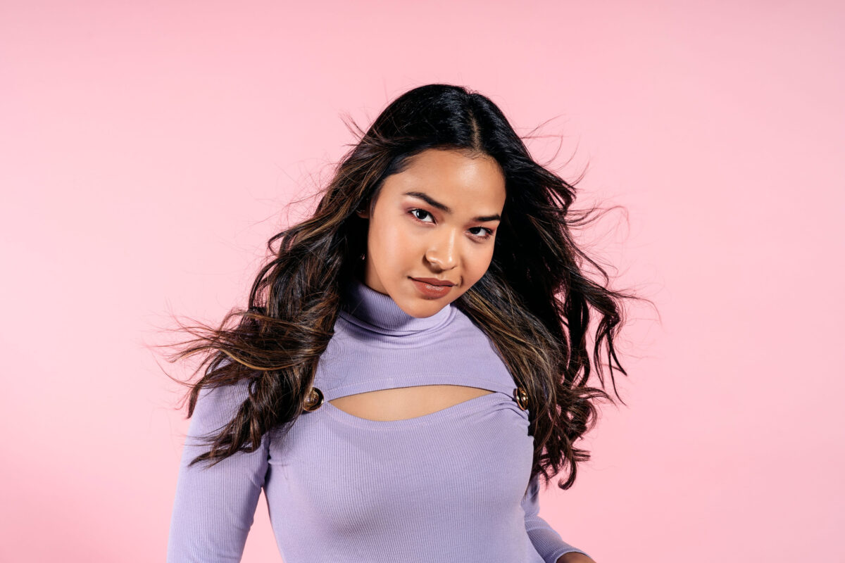 Stock photo of beautiful girl looking at camera against light pink background in studio shot.