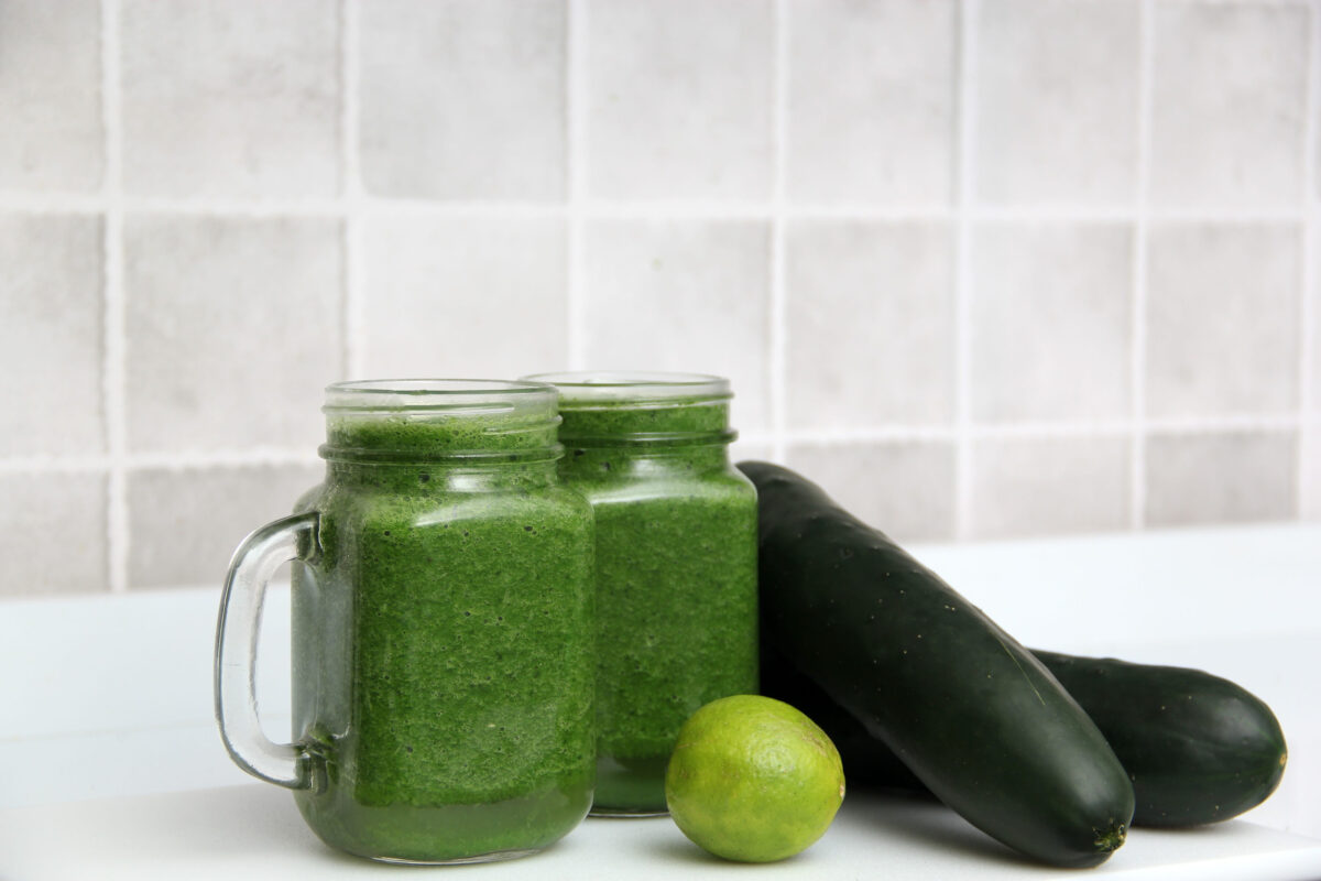 8 Popular Healthy Foods That May Be Wrecking Your Diet 4 Person in the kitchen prepares nutritious green juice in the kitchen blender, with cucumber as an ingredient, takes it out of the refractory and cuts it on wooden board