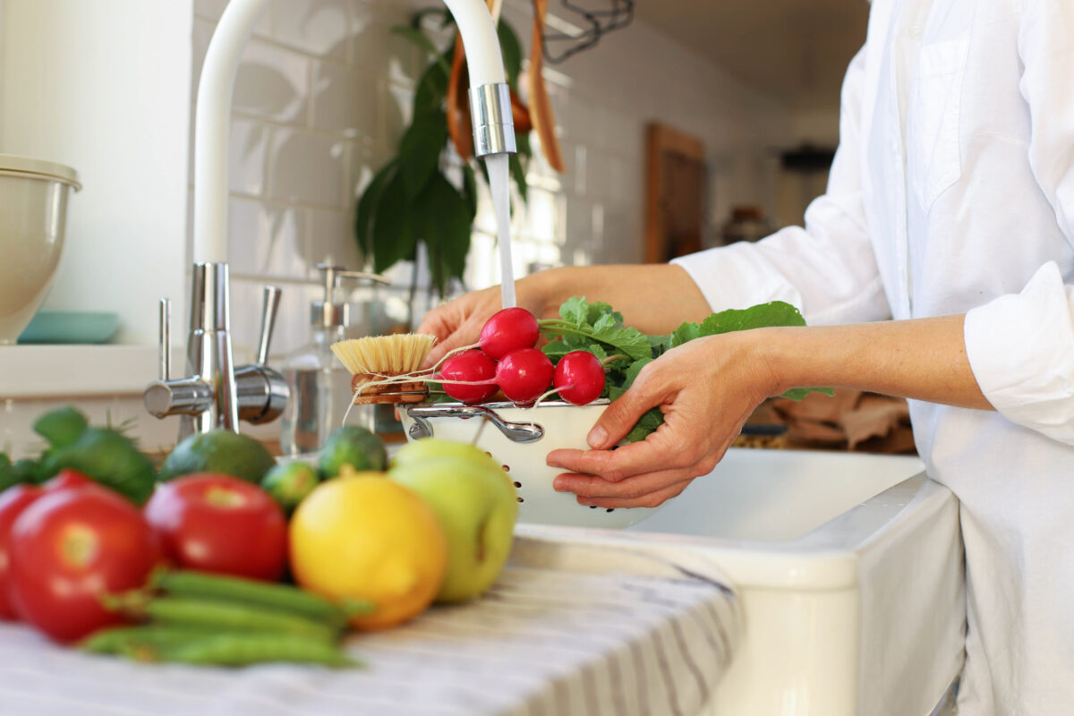 7 Kitchen Habits That Make Food Spoil Faster Than It Should 3 A young girl, a woman, has harvested in the garden, bought at the market, supermarket and washes vegetables and fruits in the kitchen sink. raw healthy food