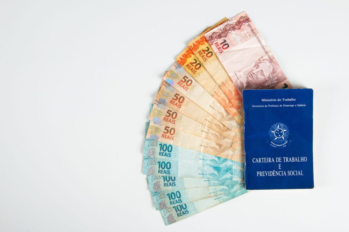 Brazilian document work and social security (Carteira de Trabalho e Previdencia Social) with Brazilian money banknotes.