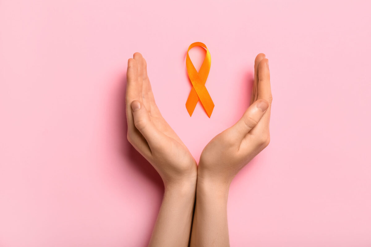Woman with orange awareness ribbon on pink background. Kidney cancer concept