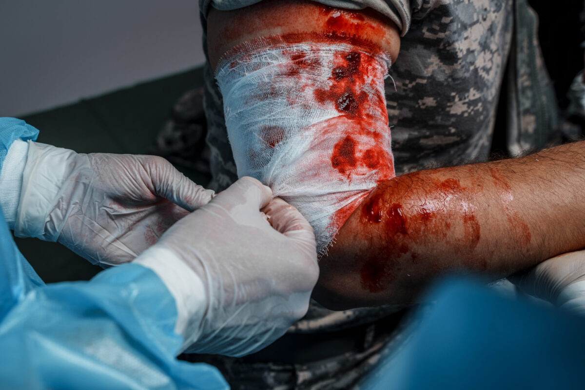 Doctor specialist bandaging injured soldier in operating room
