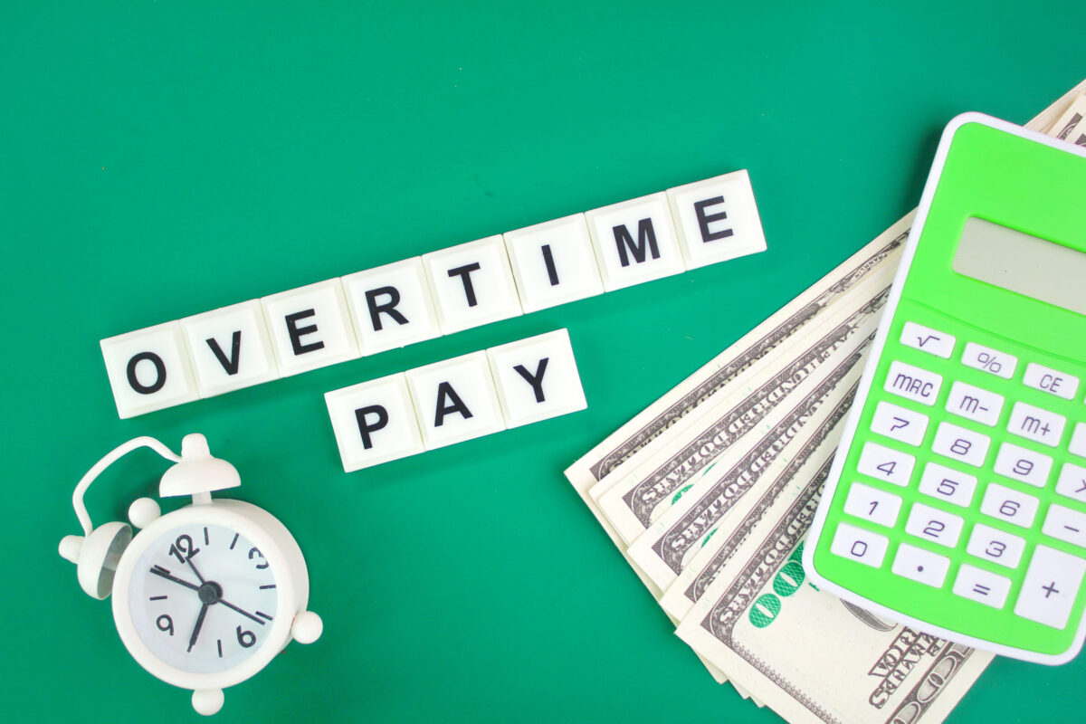 paper money, a calculator and a bell with the word overtime pay