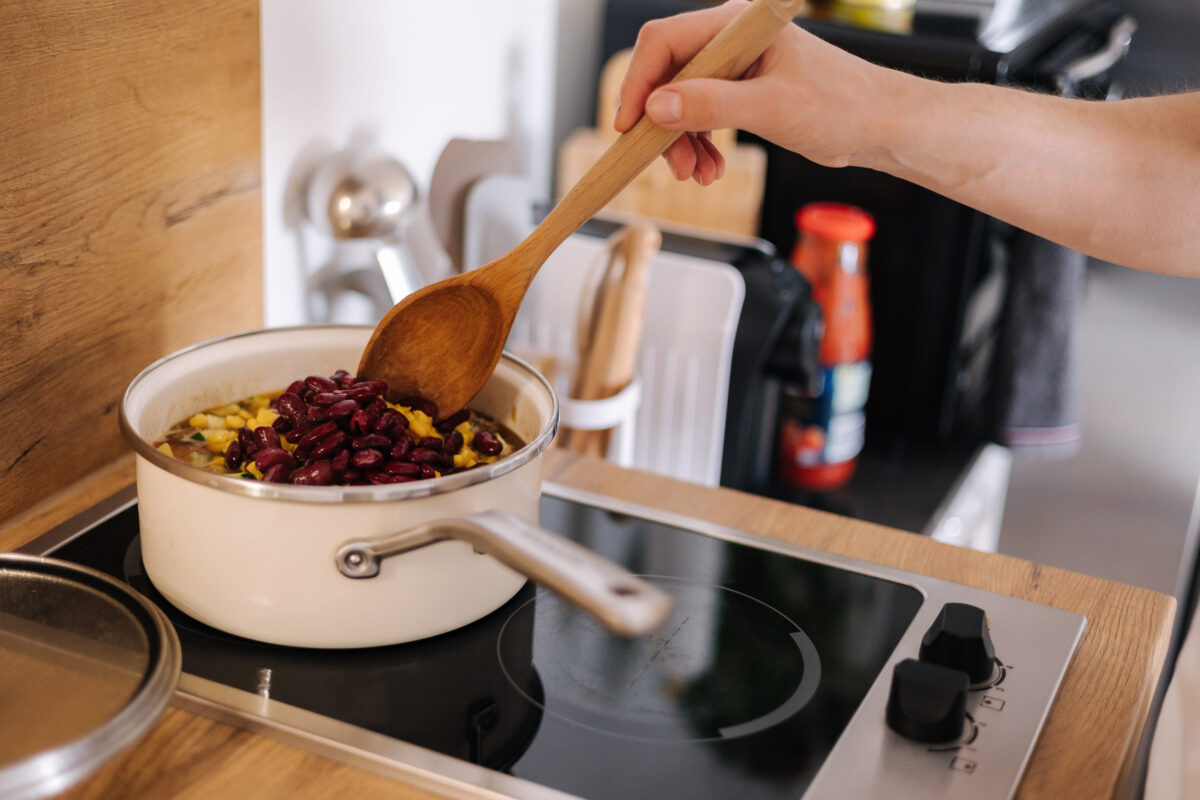 Side view of human hand stirs ingredients with a wooden spoon. Home made food concept. Kitchen