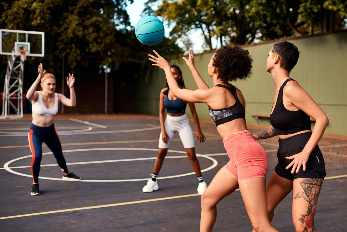 sportswomen playing a competitive game of basketball together during the day.