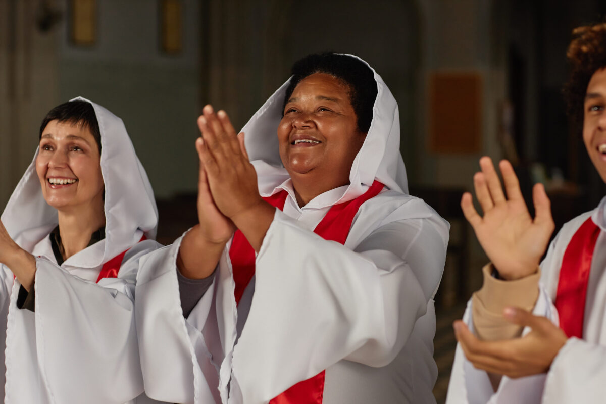 Group of happy people clapping while singing in choir in baptist church