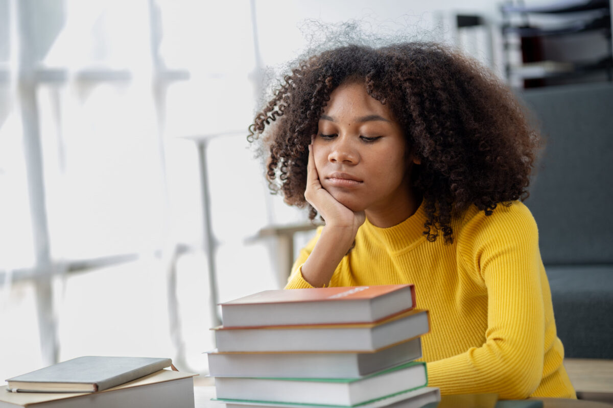 An American woman sits in the living room on weekends, with stacks of books, she is reading and studying for exams. Student concept, students reading, studying.