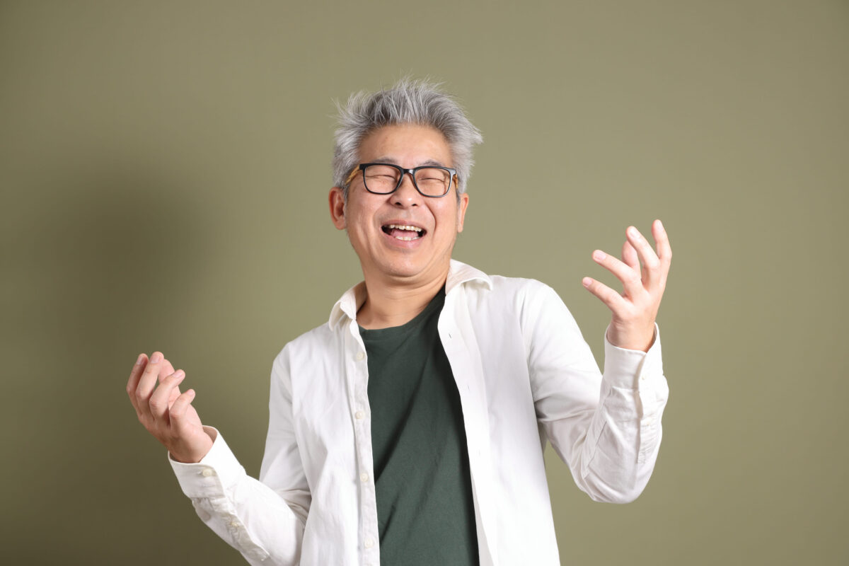 A half-body portrait of an East Asian businessman, isolated against a deep green background, taken in a studio.