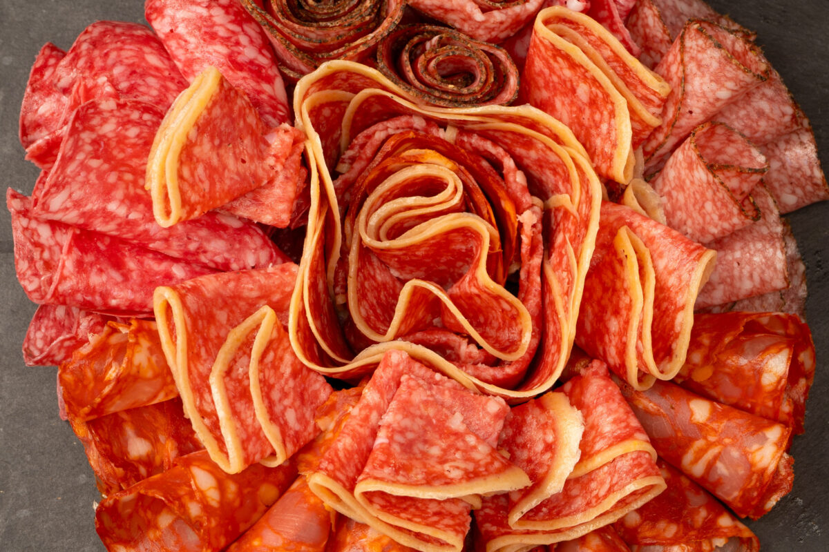 Different kinds of meat cuts on a board. On a black background.