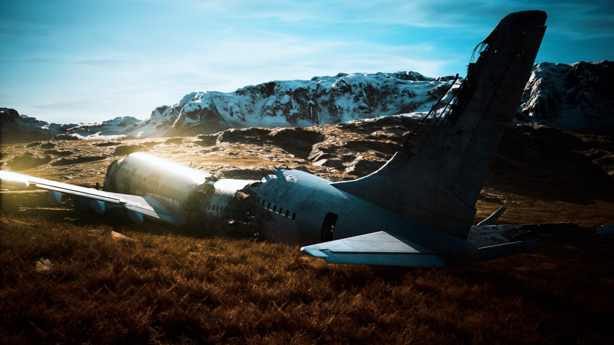 An old aircraft lies wrecked on rocky ground, surrounded by golden grass and majestic snowy mountains. The blue sky above adds a serene beauty to the haunting scene.