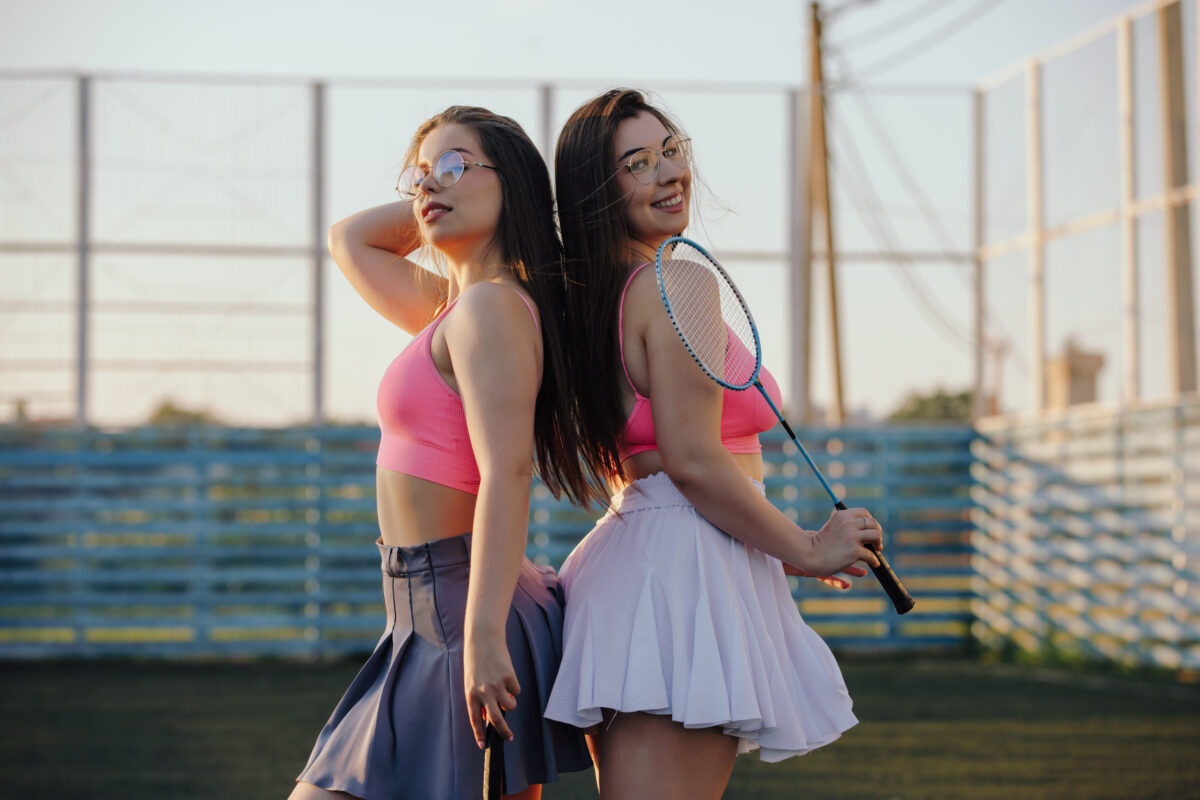 Girls badminton players in skirt posing on the tennis court