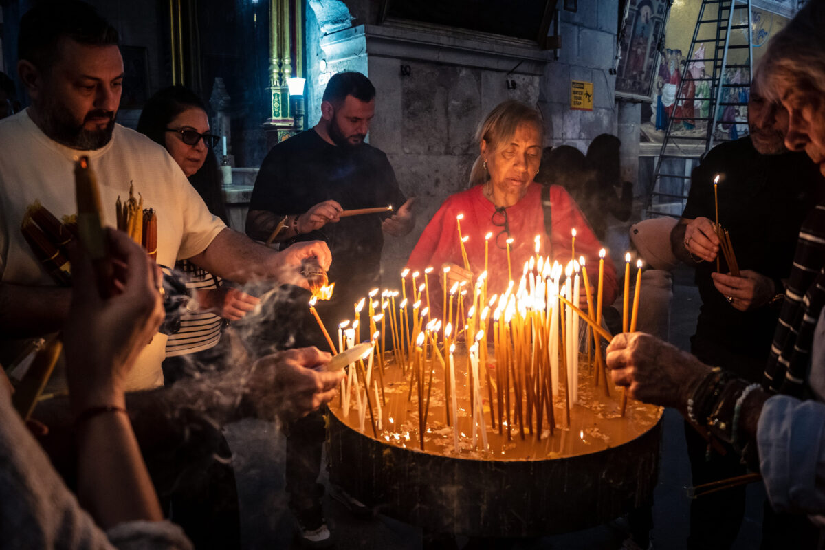 JERUSALEM, ISRAEL - FEBRUARY 21, 2026 Christian pilgrims lighting prayer candles in the mystic and sacred darkness of the Church of the Holy Sepulchre. Spiritual atmosphere and deep religious fervor.