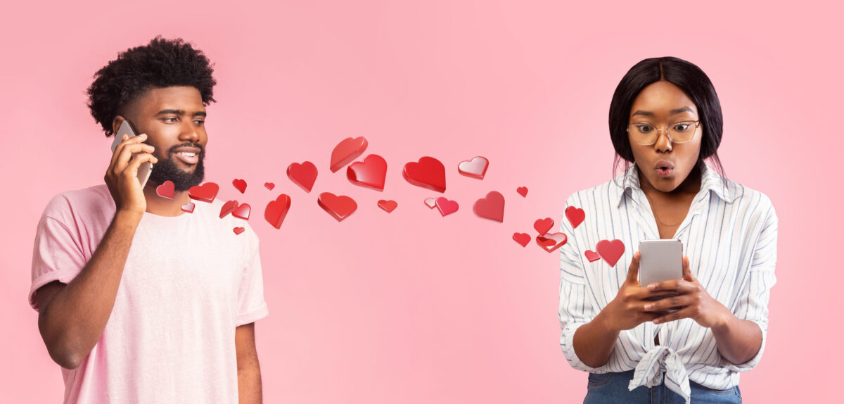Guy Talks on Phone With Relaxed Look While Heart Icons Flow Towards Woman on Pink Background
