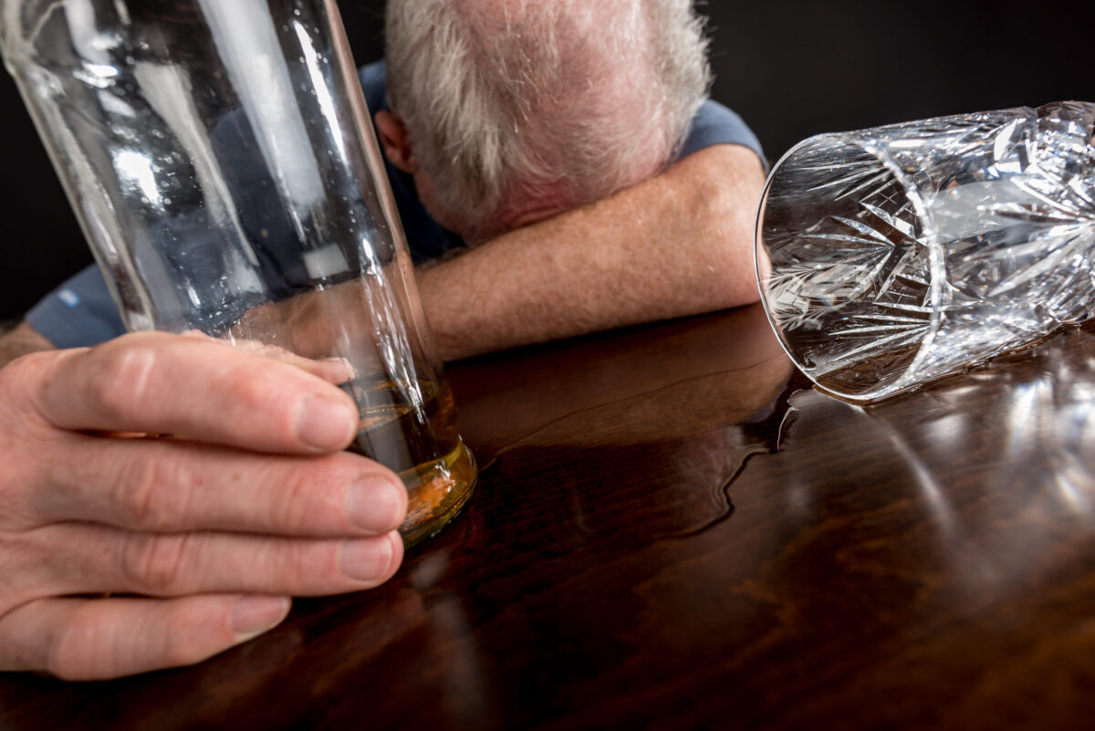 Drunk man slumped on table after alcohol abuse