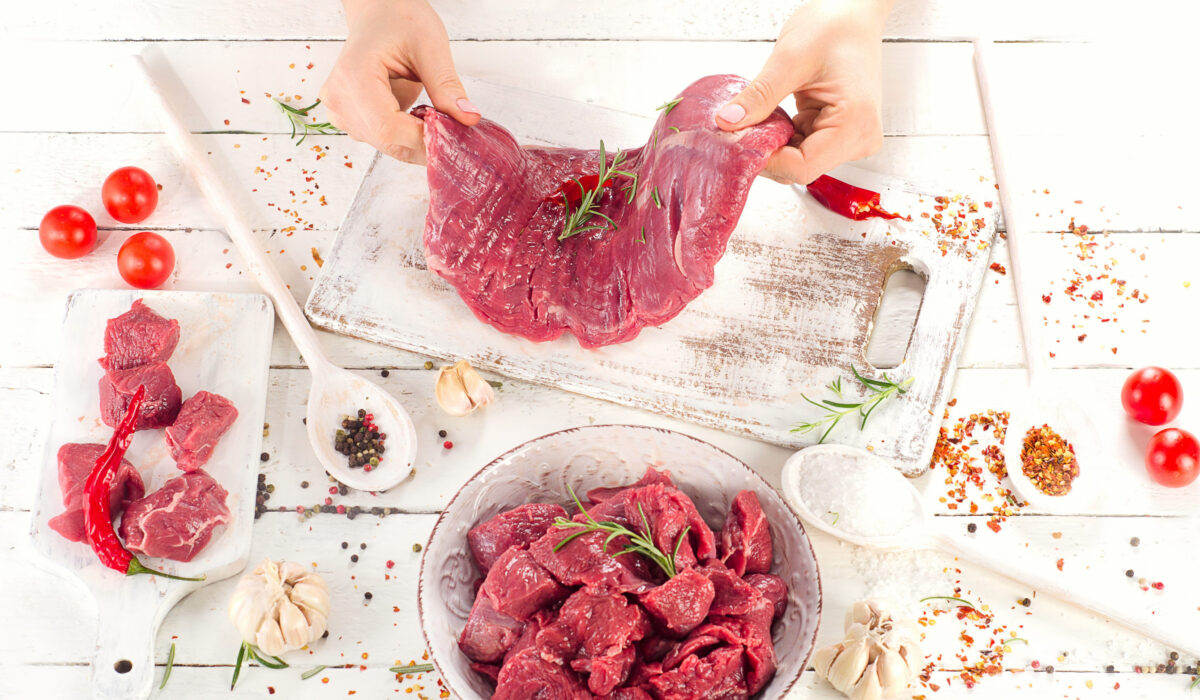 Woman hands with Raw beef on wooden background. Top view