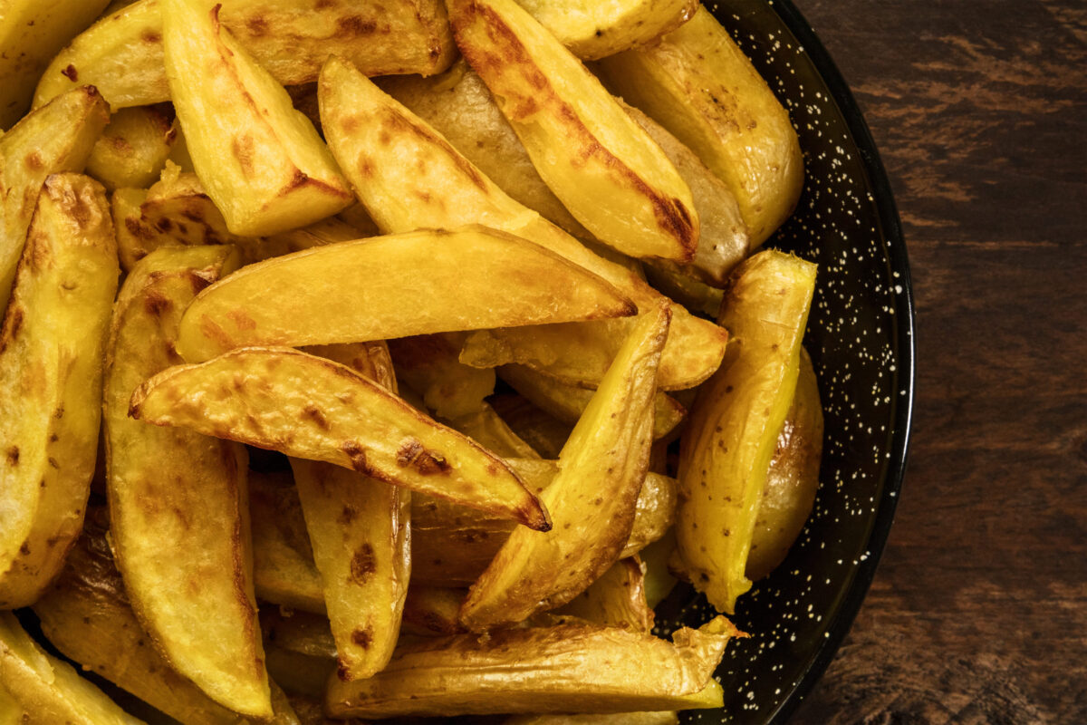 Crunchy roasted potatoes in skillet on dark rustic texture