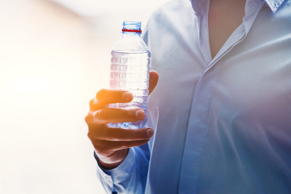 mans hand with bottle of water in sunlight