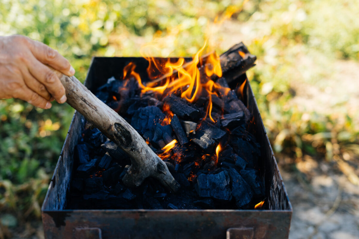 on a picnic in nature a man kindles a fire in a barbecue