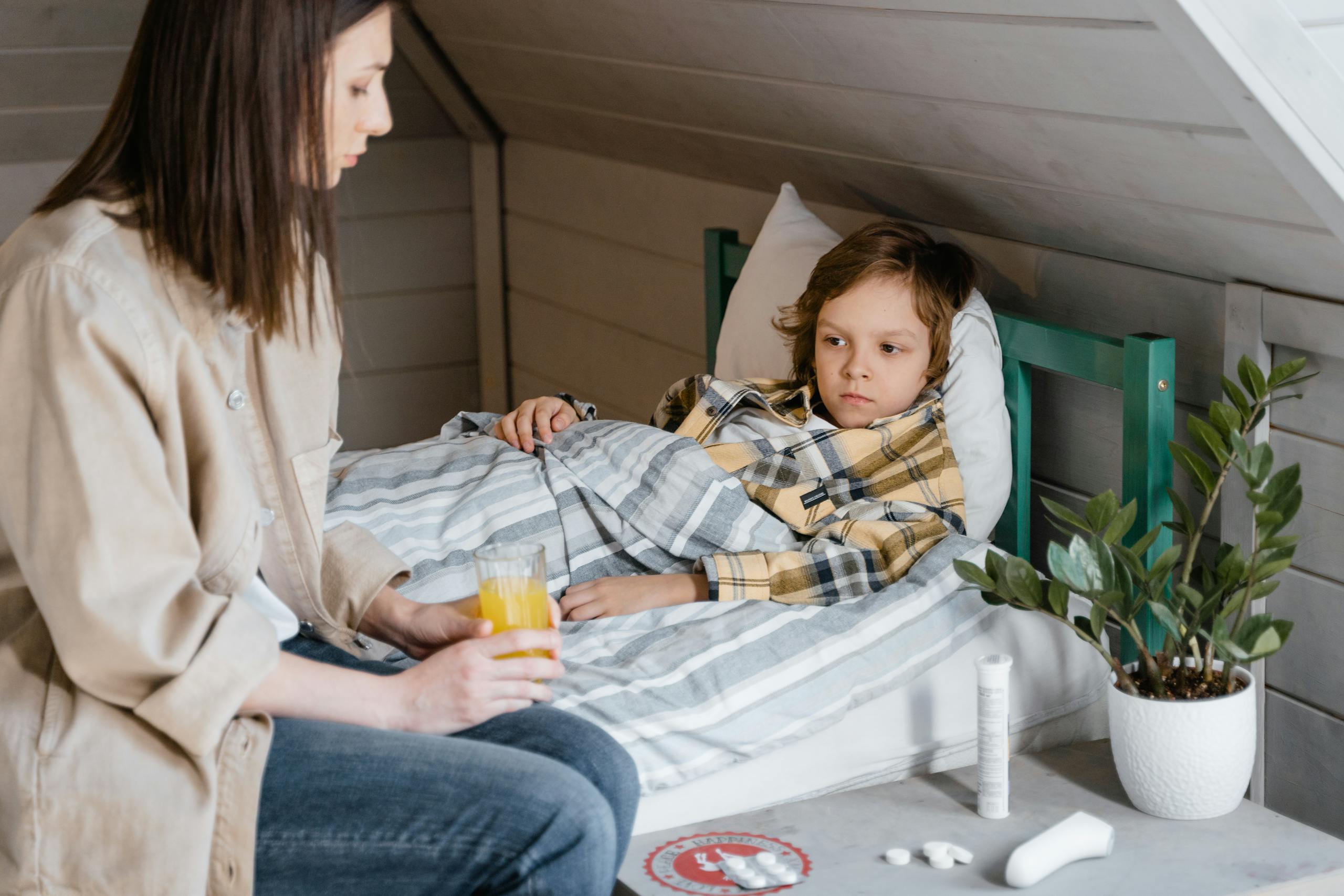 8 Shocking Ways Grandparents Are Becoming the New Childcare System 3 A caring mother gives orange juice to her child resting in bed, providing comfort and care.