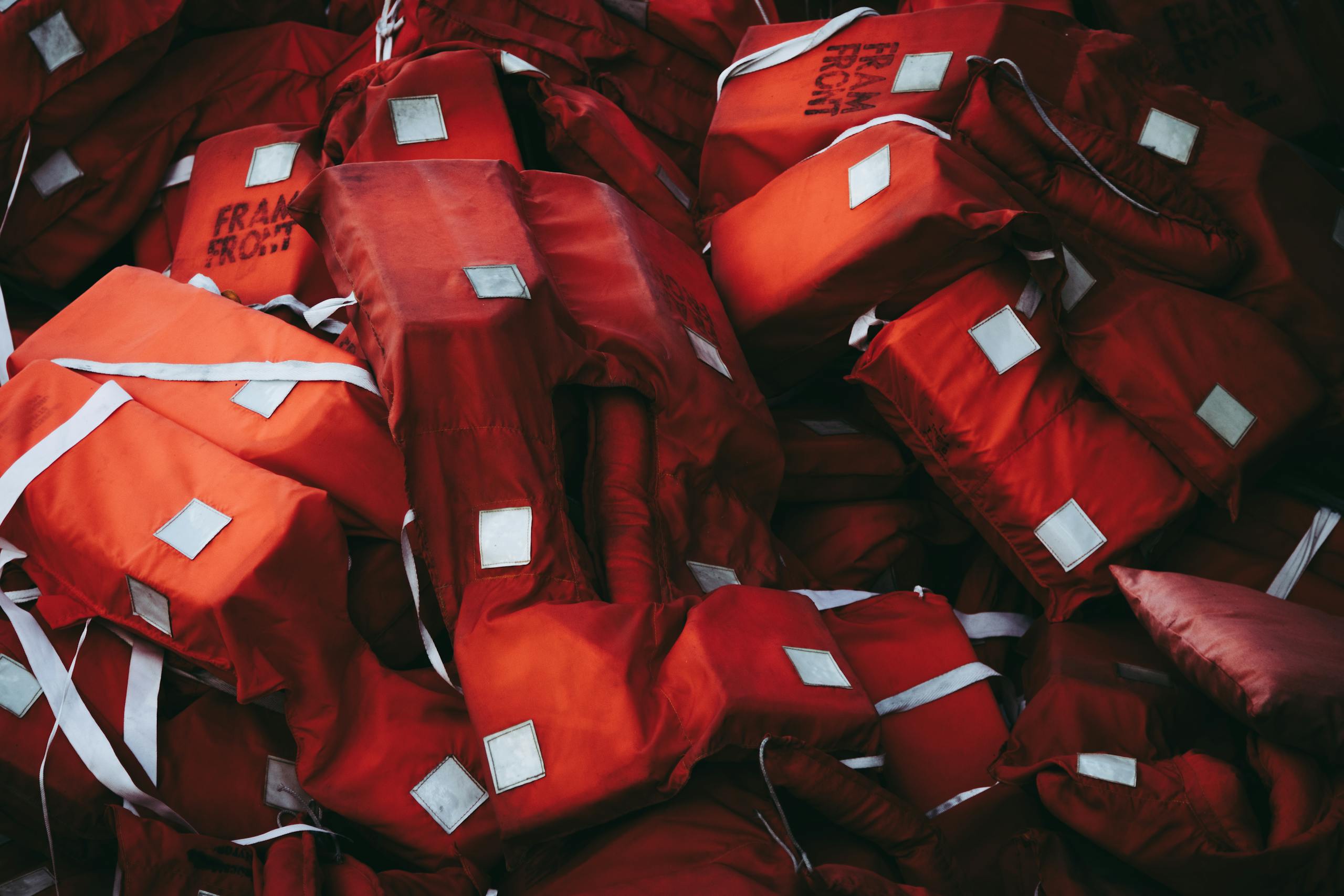A collection of red life jackets emphasizing safety and emergency preparedness.