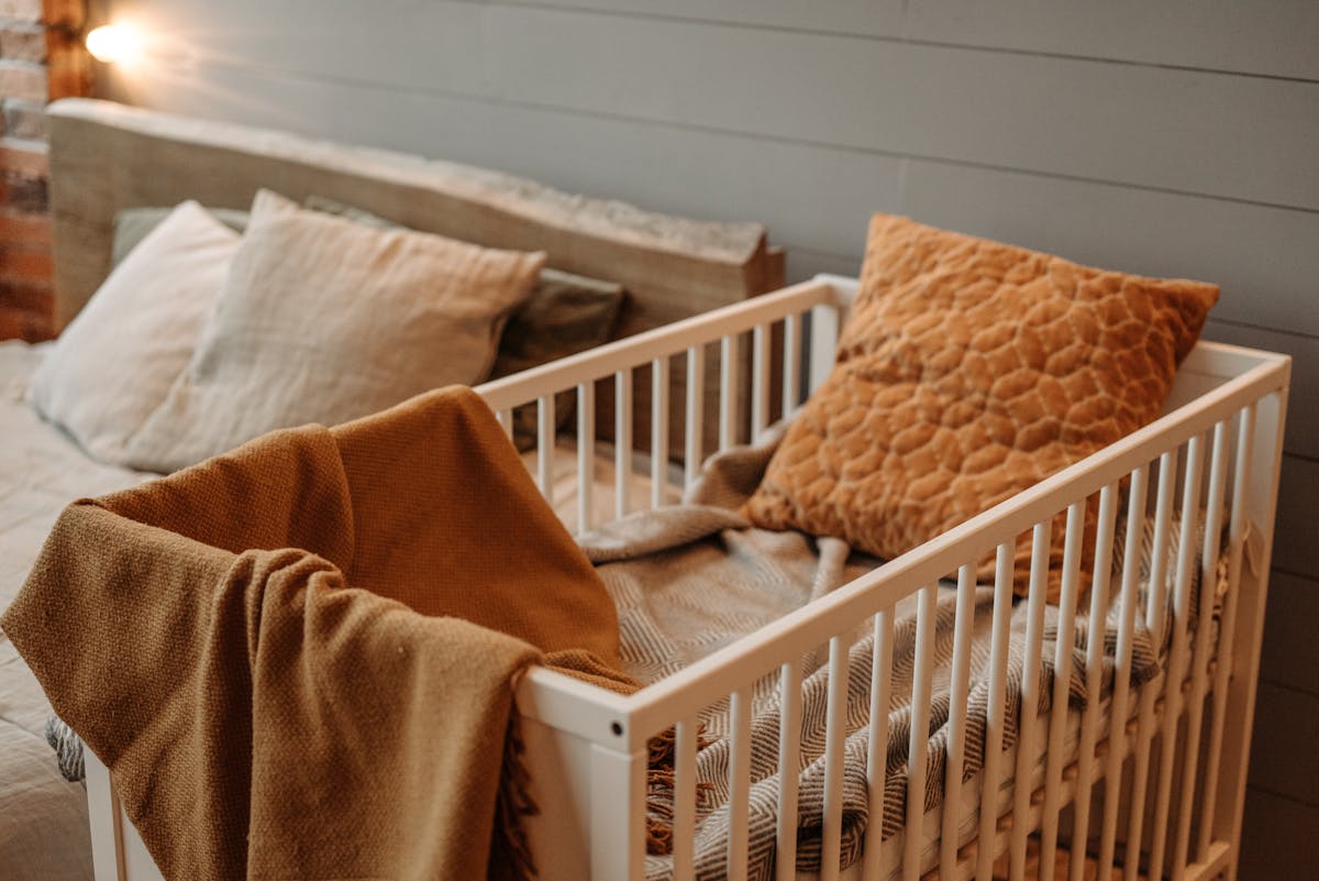 8 Secondhand Deals That Could Turn Into Costly Regrets 2 A cozy bedroom featuring a white crib with warm blankets and pillows, creating a comfortable ambiance.