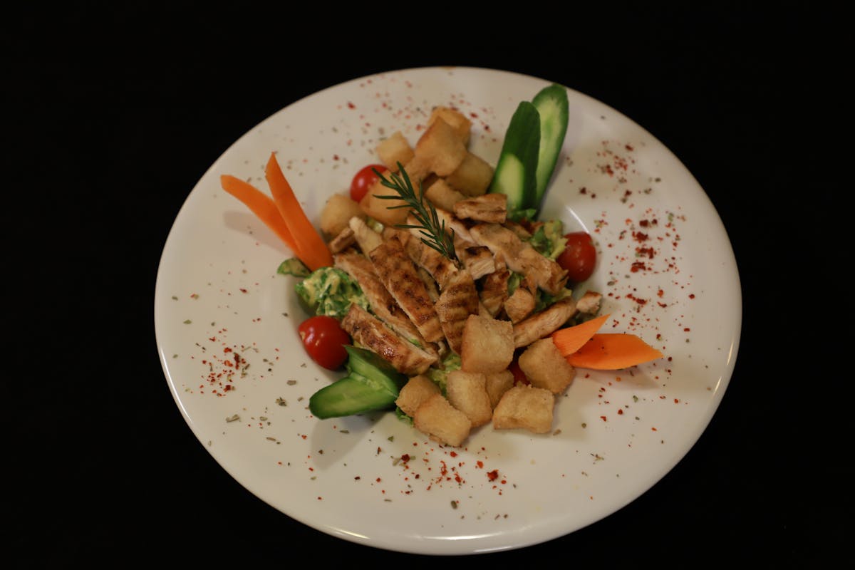 10 Cheap Summer Meals That Keep Families Fed Without Breaking the Bank or Losing Their Minds 3 A delicious grilled chicken salad with fresh vegetables and croutons on a plate.