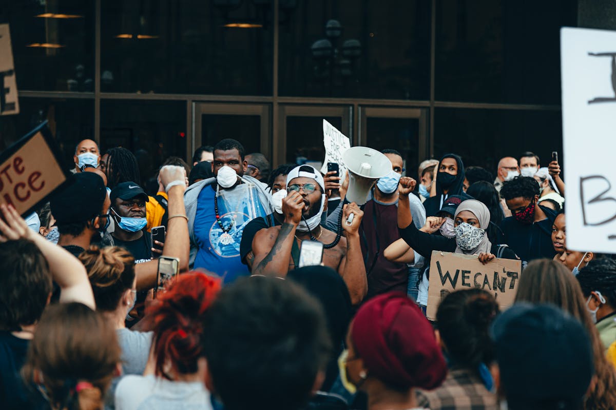 A diverse crowd at a protest for racial justice in Minneapolis, USA, demonstrating with signs and megaphones.