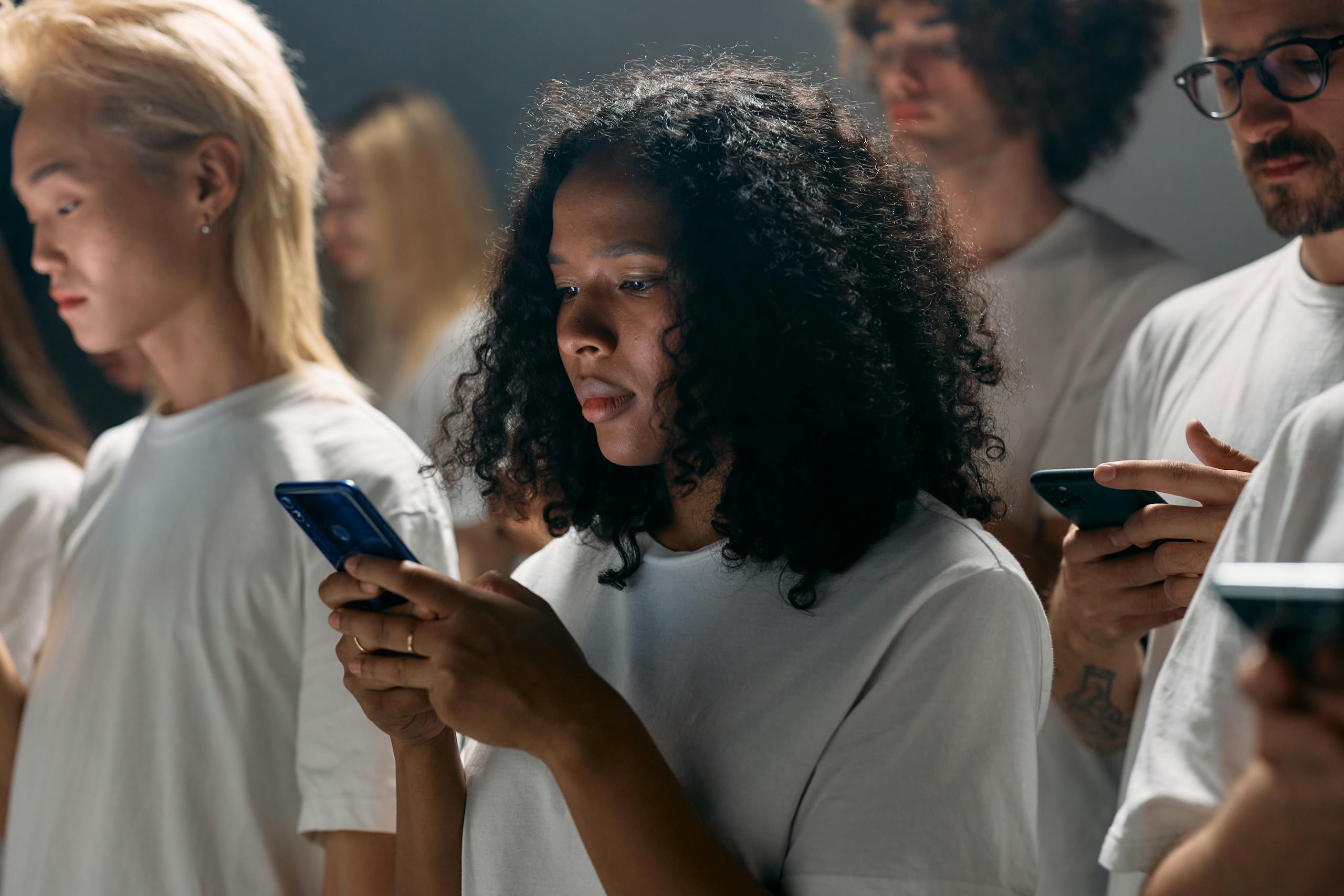 8 Creepy Ways AI Images Are Changing How People See Themselves Online 3 A diverse group of young adults focused on smartphones, symbolizing modern social connections and technology.