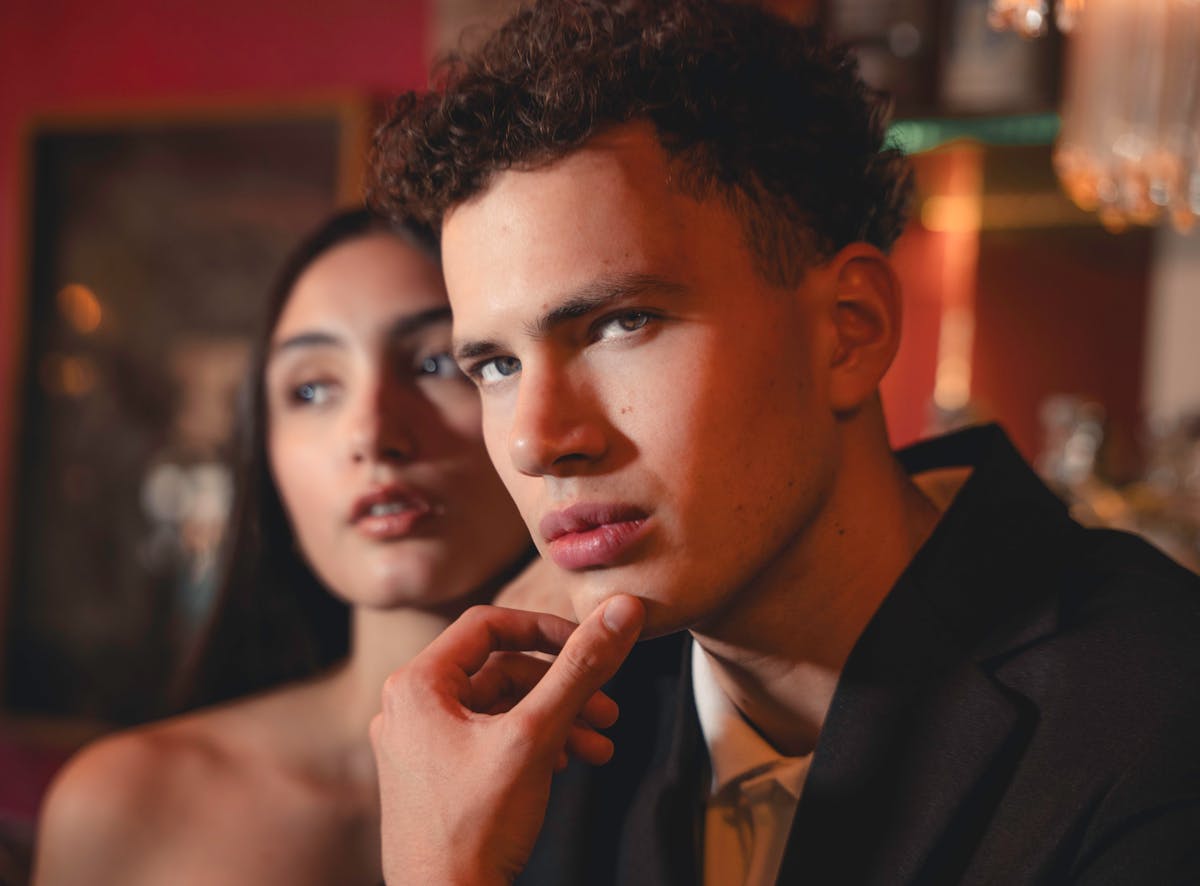 7 Disturbing Thoughts Some Men Admit Having About Revealing Sports Uniforms 3 A fashionable couple in formal attire with an intense expression in a moody setting.