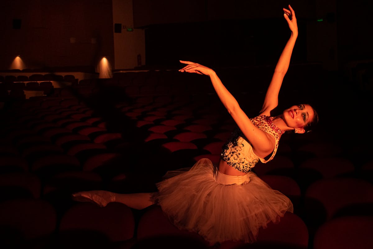 A graceful ballerina elegantly performing in an atmospheric theater setting.