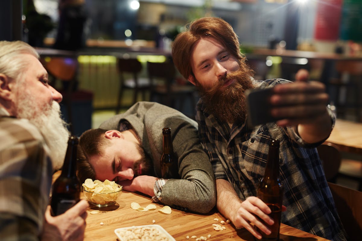 8 Disturbing Truths About Getting Drunk 2 A group of friends enjoying drinks and snacks while taking a selfie inside a pub.