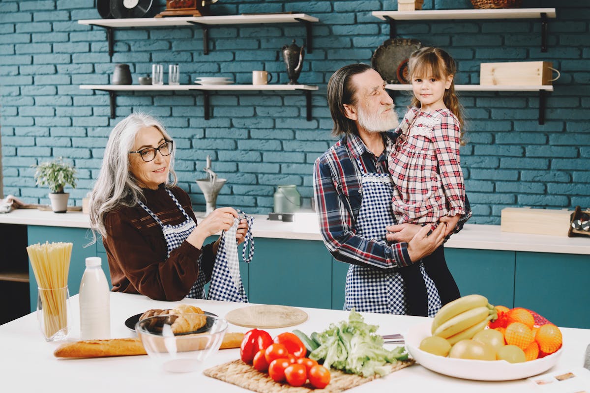 A joyful family scene in a modern kitchen with grandparents and grandchild cooking together.
