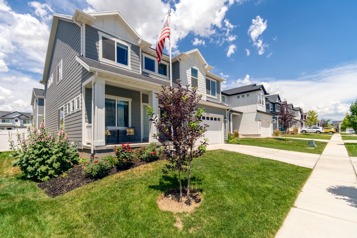A modern suburban house with garden and American flag, showcasing beautiful architecture.