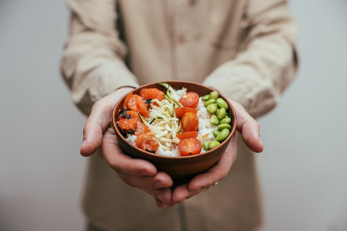10 Cheap Summer Meals That Keep Families Fed Without Breaking the Bank or Losing Their Minds 4 A nutritious bowl of rice topped with fresh vegetables held in hands.