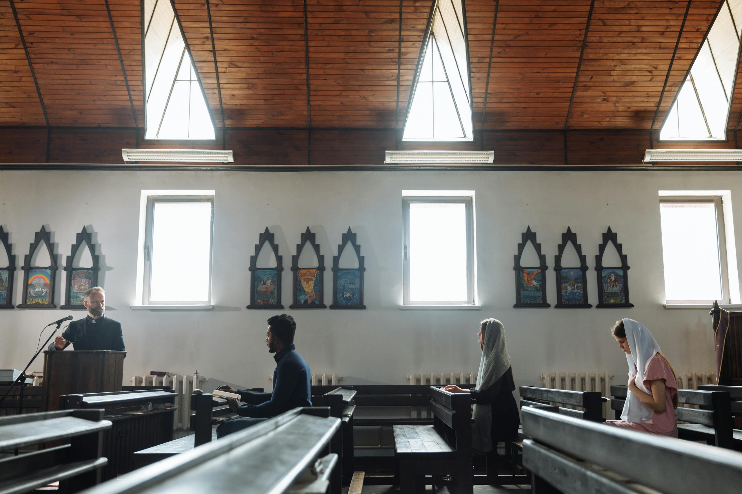10 Harsh Truths About Why Church No Longer Feels Like Home to Some Americans 4 A serene church interior with people praying and a priest presiding from a pulpit.