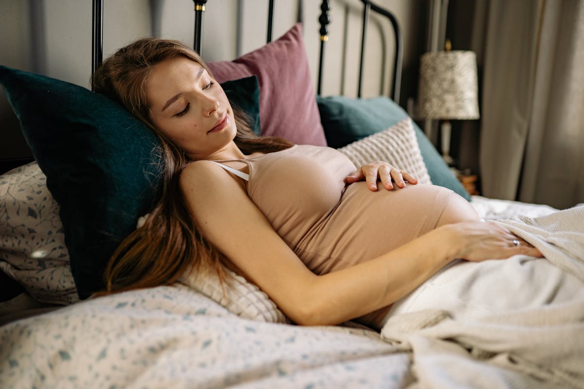 A serene pregnant woman resting in bed, showcasing relaxation and comfort.