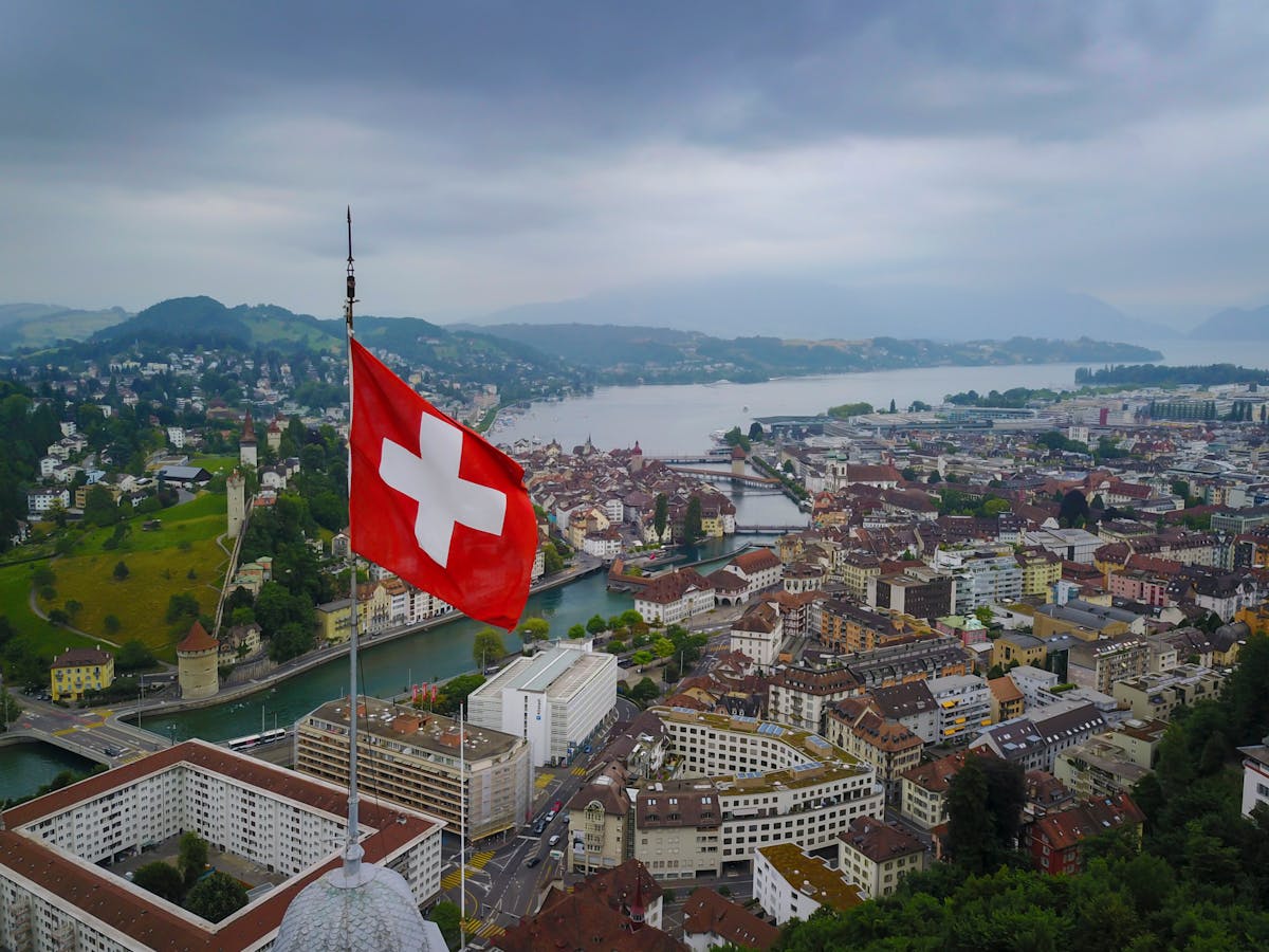 The Best Countries To Live In And Work Abroad 2 A stunning aerial view of Lucerne, Switzerland with a Swiss flag and scenic lake backdrop.