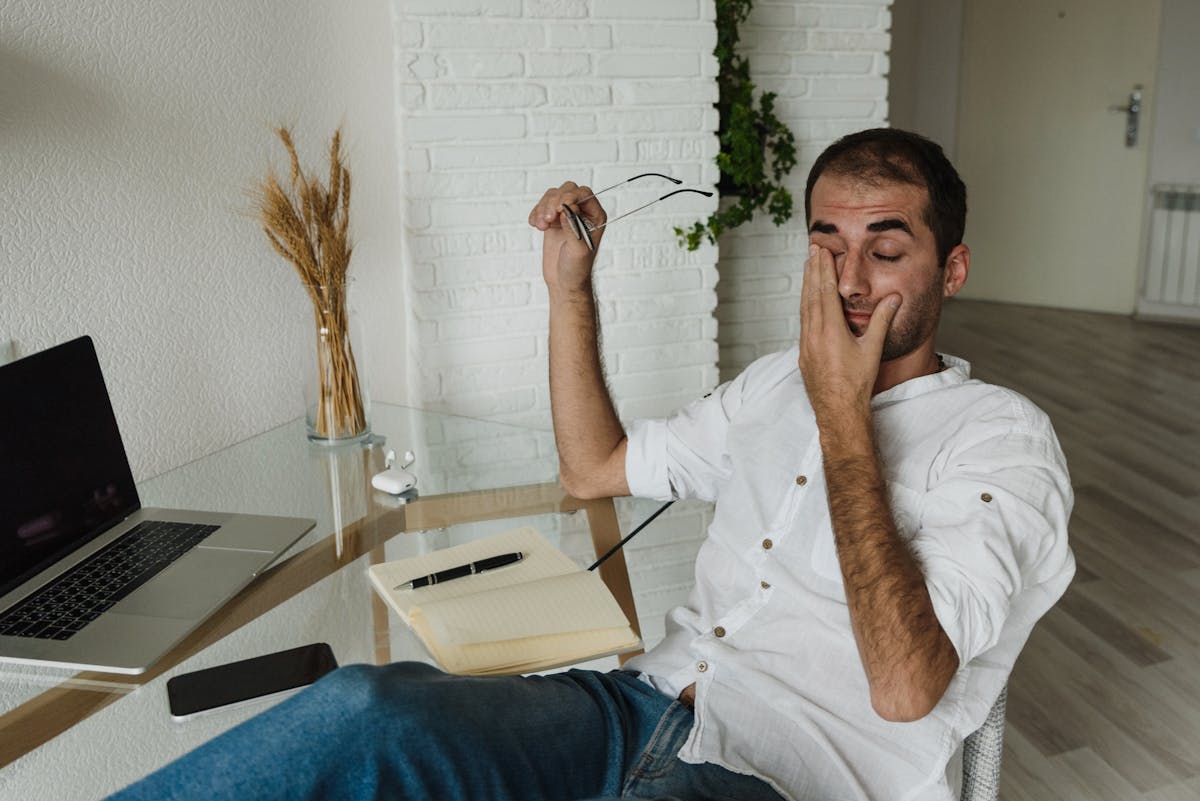 10 Alarming Symptoms of Hantavirus You Need to Recognize Amid the Ship Outbreak 1 A tired man in a white shirt rests at a home office desk, holding eyeglasses and rubbing his eyes.
