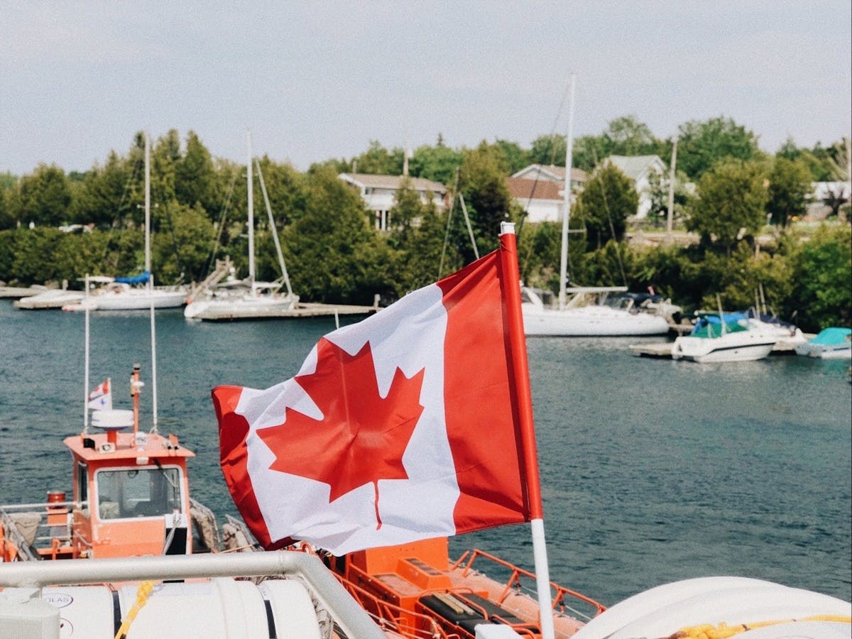 The Best Countries To Live In And Work Abroad 3 A vibrant Canadian flag waving at a harbor with boats nearby during a summer day canada