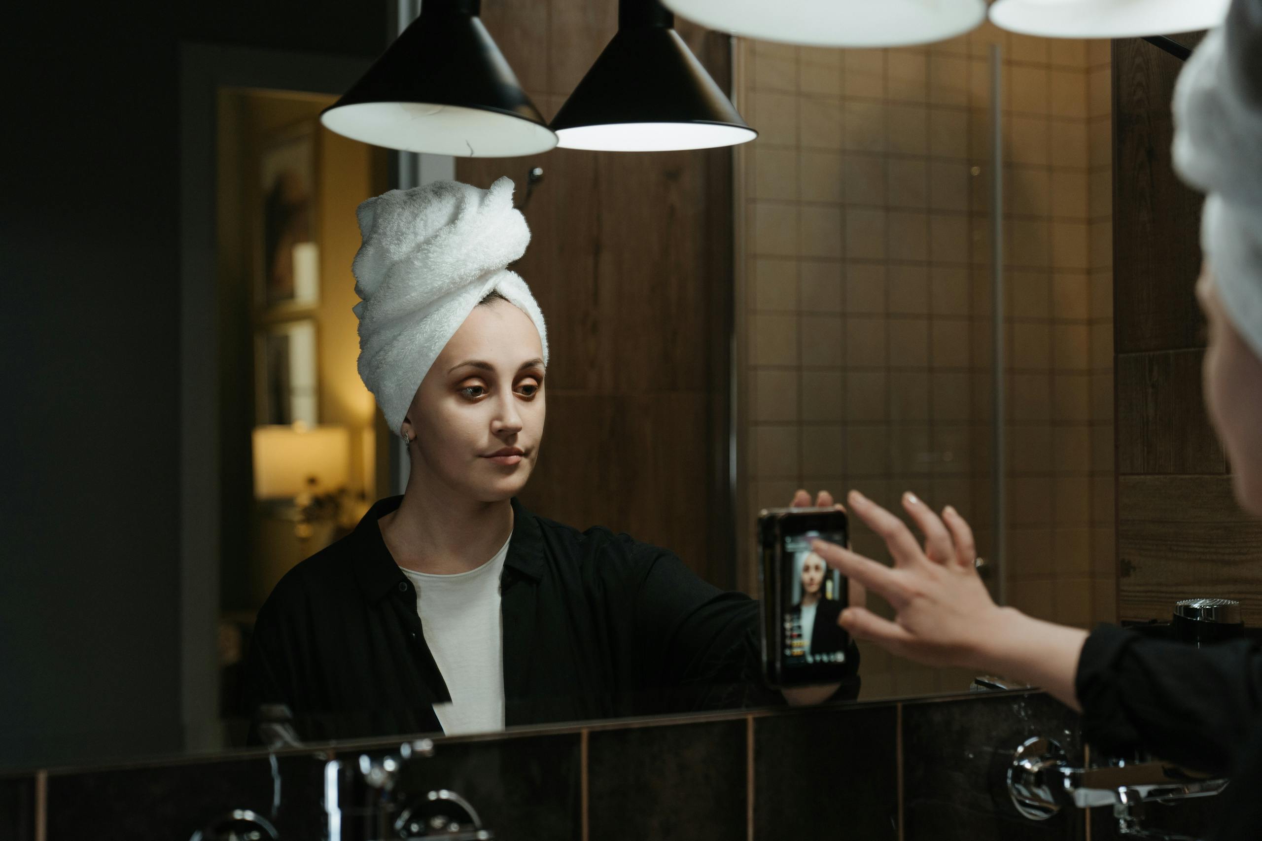 8 Creepy Ways AI Images Are Changing How People See Themselves Online 2 A woman with a towel on her head takes a selfie in a stylish bathroom mirror.