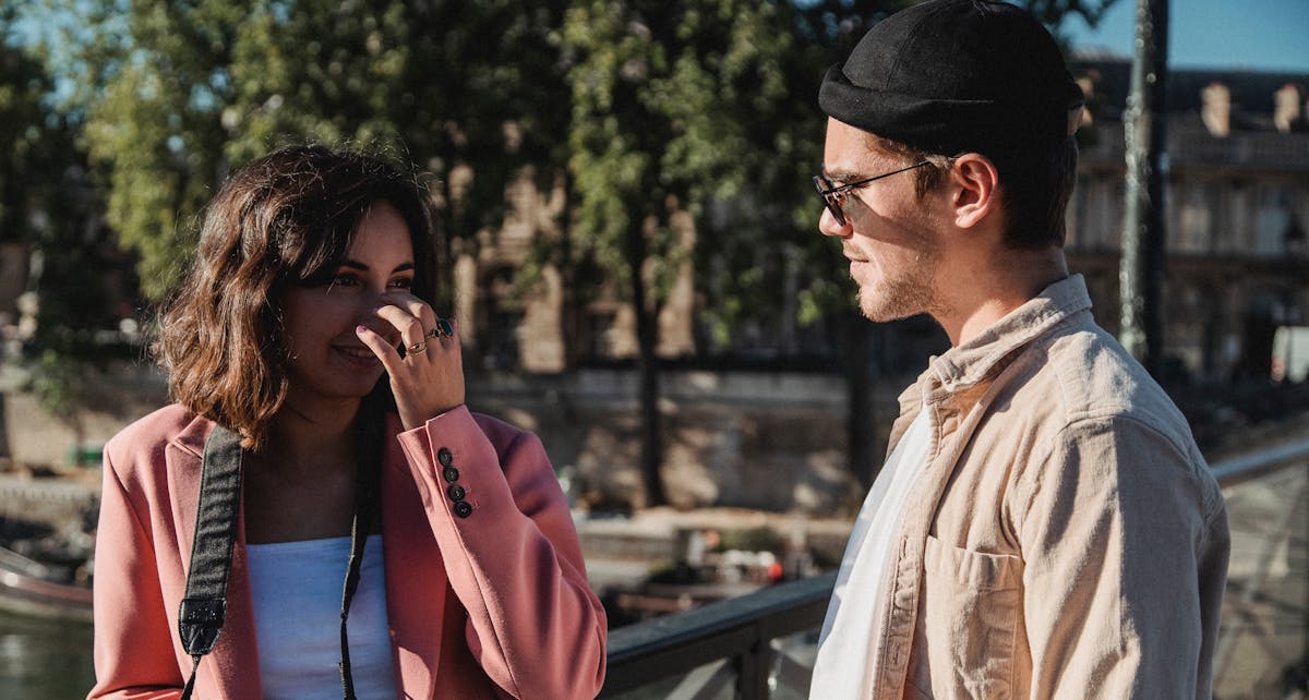 13 Costly Nice Guy Mistakes That Quietly Turn Women Off 6 A young couple conversing and enjoying the sunshine in a scenic outdoor setting.