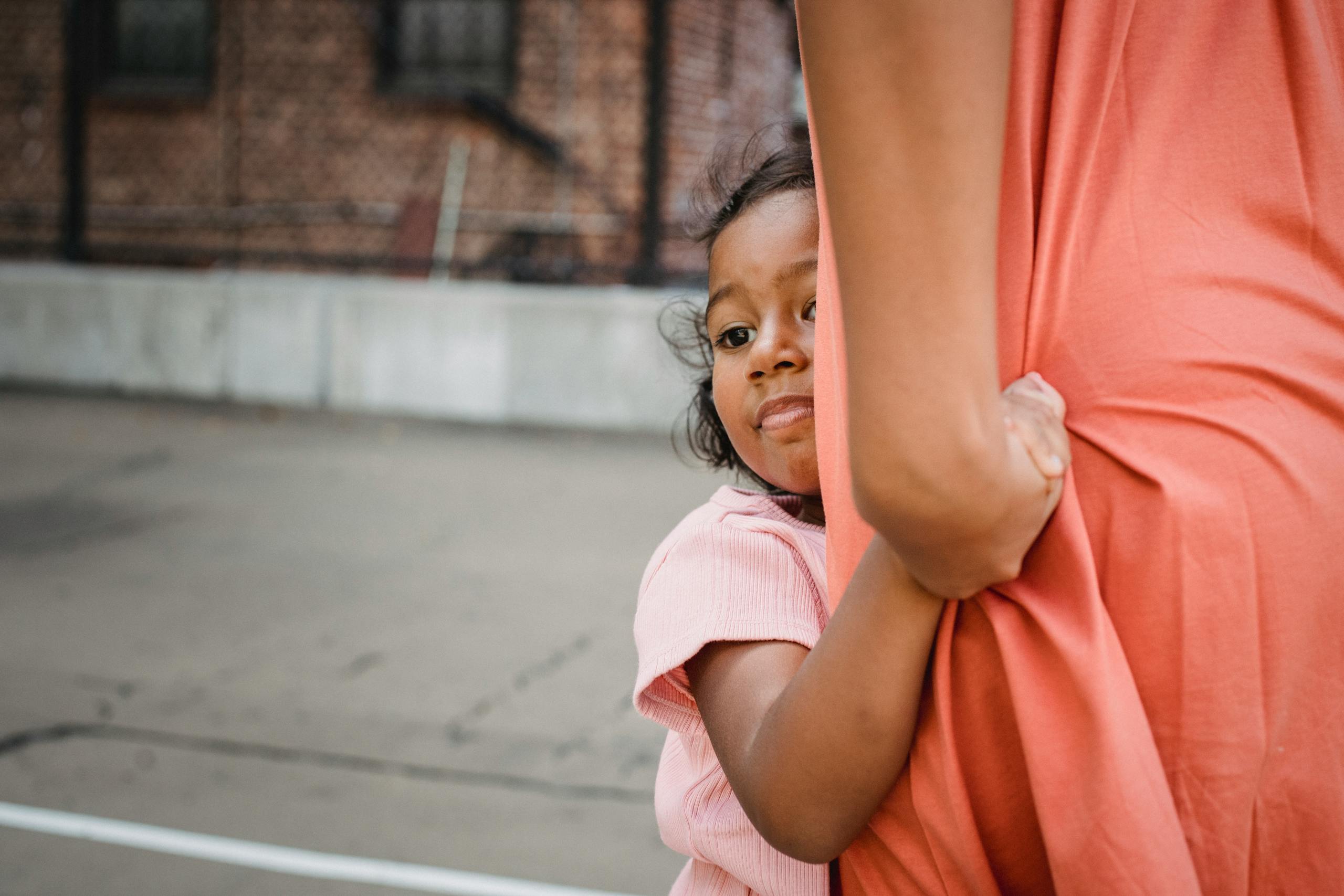 7 Ways America’s Immigration Fight Is Tearing Ordinary Communities Apart 3 A young girl hugging her mother tightly outdoors, conveying warmth and affection.