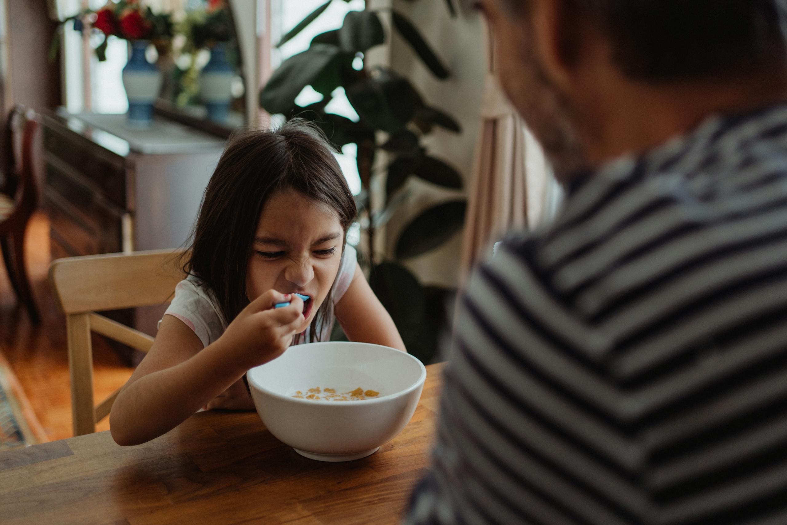 7 Ways America’s Immigration Fight Is Tearing Ordinary Communities Apart 1 A young girl making a funny face while eating cereal for breakfast at home.