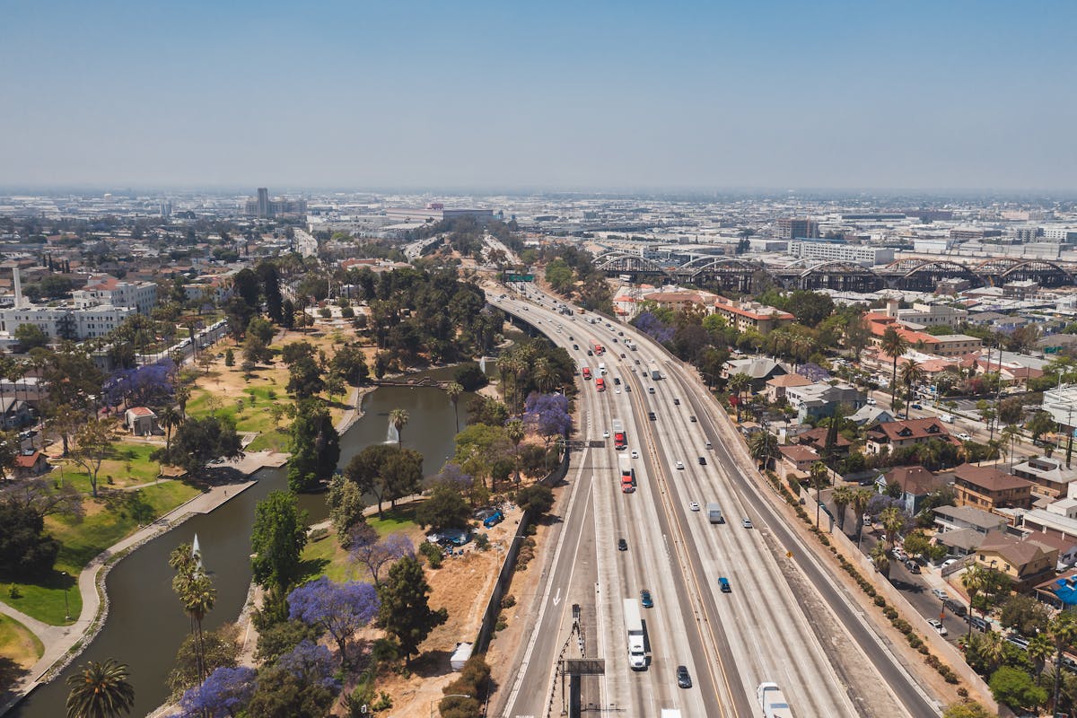 12 Dangerous Places in the U.S. We Wouldn’t Wish on Our Worst Enemy 4 Aerial view of a busy Los Angeles freeway flanked by a verdant park and urban landscape.