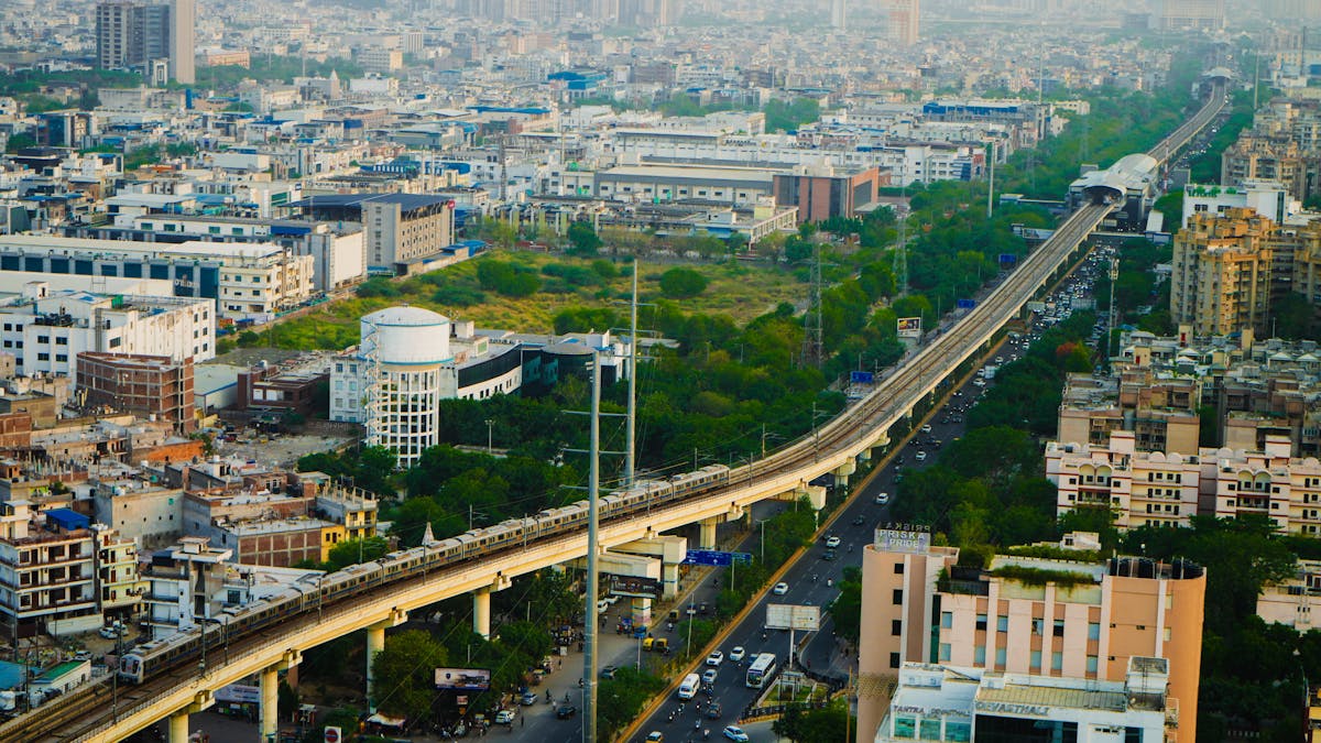8 Cities With the Worst Air Quality Globally 4 Aerial view of a metro train traversing an urban cityscape with dense buildings and greenery.